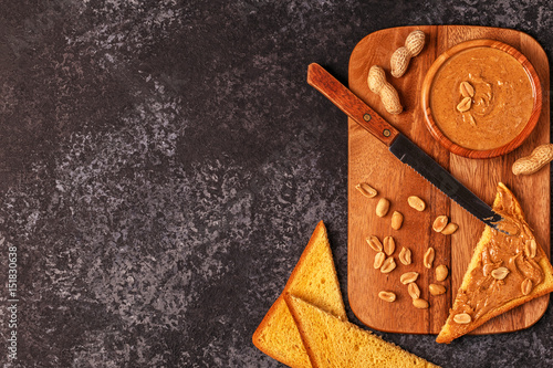 Bowl of peanut butter on wooden board.