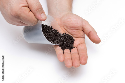 Принти на полотні Plastic pellets spilled out of the measuring Cup on a man's hand