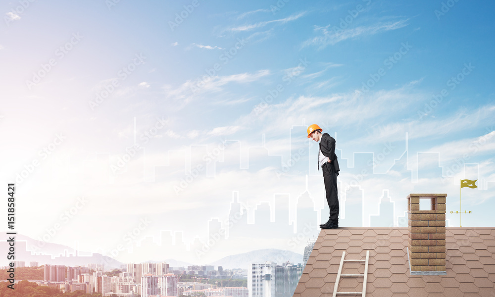 Engineer man standing on roof and looking down. Mixed media Engineer man standing on roof and looking down. Mixed media