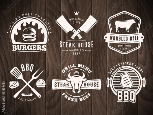 BBQ, burger, grill badges. Set of vector barbecue logos. Retro emblems for steak house or grill bar on vintage wooden background.