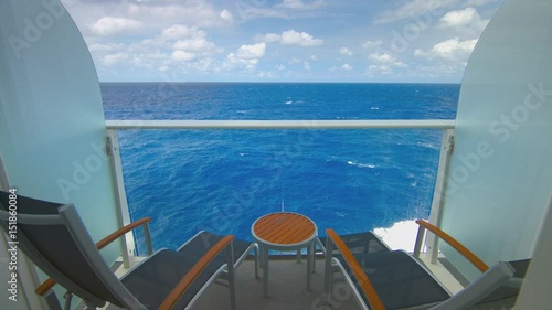 Cruise Ship Balcony with Furniture View Sailing on Tropical Water with Passing Waves during an Idyllic Day with White Clouds in a Blue Sky