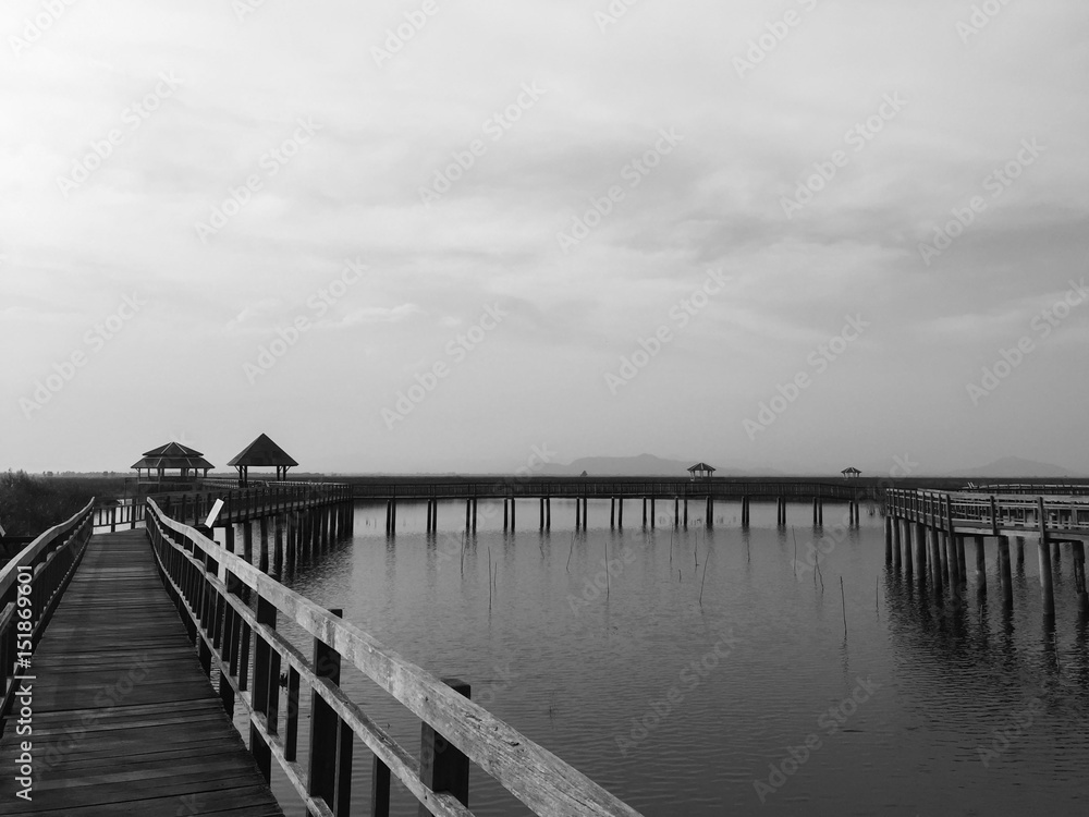 Fototapeta premium Piękny krajobraz z drewnianym mostem, domem, jeziorem i górami, Bueng Bua w Parku Narodowym Sam Roi Yot, Prachuap Khiri Khan Tajlandia