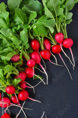 Food background. Fresh, young radish with greens on a black background. Bio food.