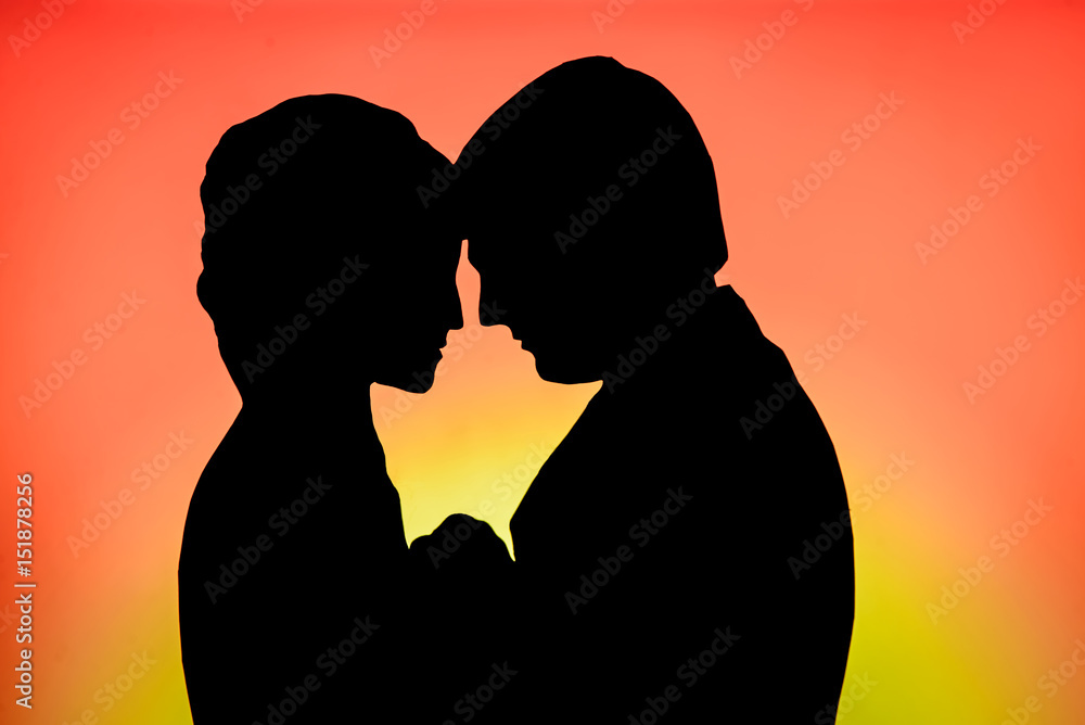 Cut paper silhouette of loving couple on a bright red yellow background