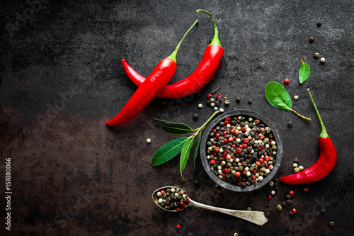 Fotografia Red hot chili pepeprs and peppercorns on black metal background, top view