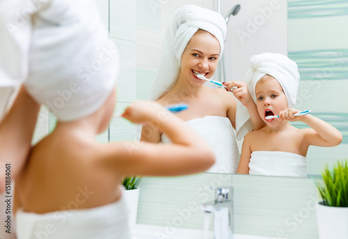 Mother and child daughter brush their teeth with toothbrush