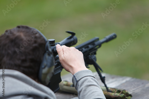 The sniper rifles his rifle and prepares for a shot in the forest on the table.