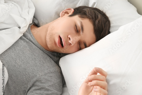 Handsome young man sleeping in bed at home photo