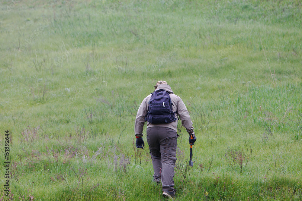 Male traveler with an ax and a backpack on a background of green mountains and firewood. Male traveler with an ax and a backpack on a background of green mountains and firewood.
