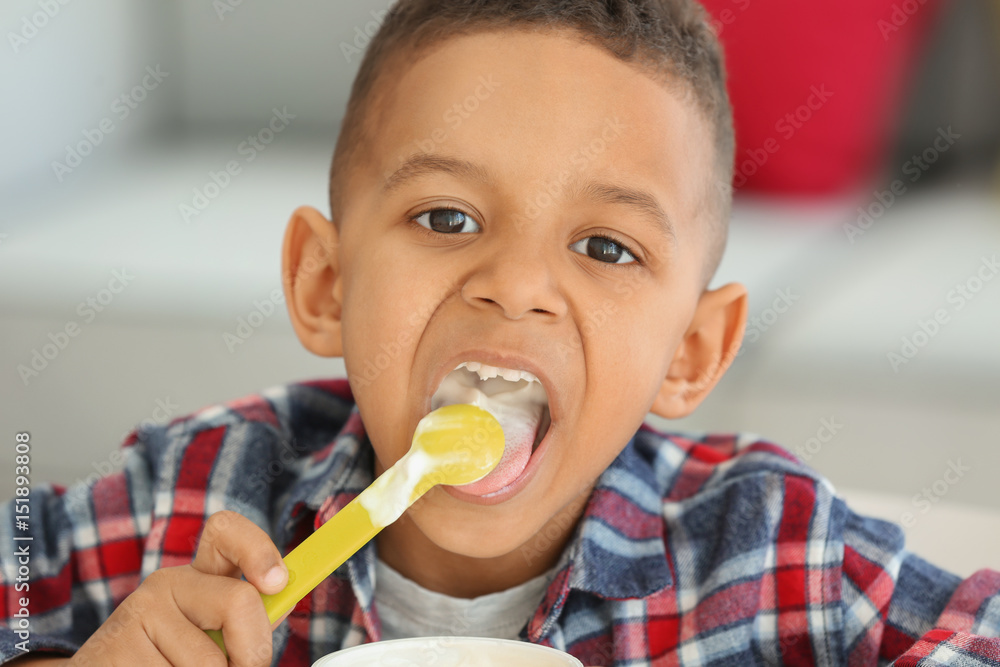 Cute African American boy eating yogurt at home, closeup Cute African American boy eating yogurt at home, closeup