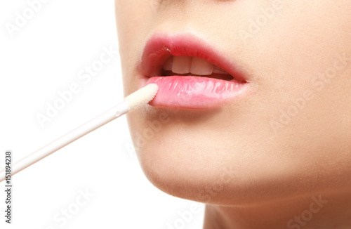Beautiful young woman applying lipstick on white background  closeup