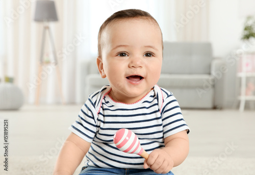 Billede på lærred Cute little baby with rattle at home