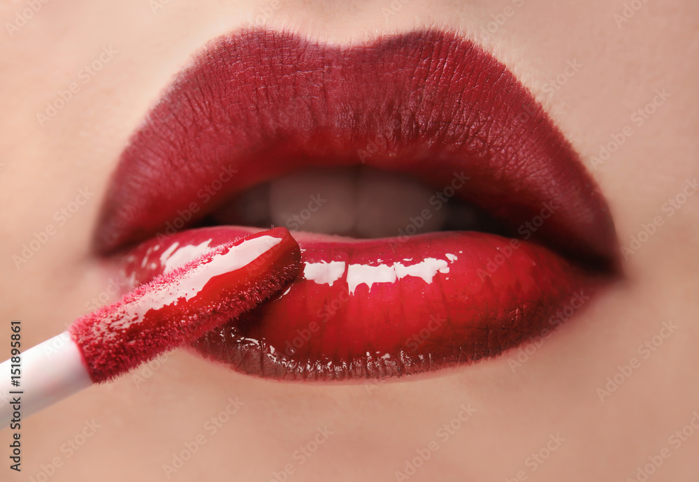Woman applying red lipgloss, close up Woman applying red lipgloss, close up