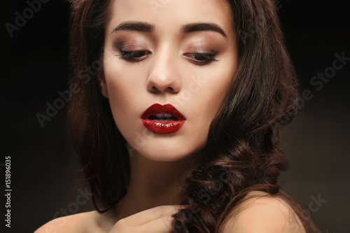 Portrait of beautiful woman with red lips on dark background