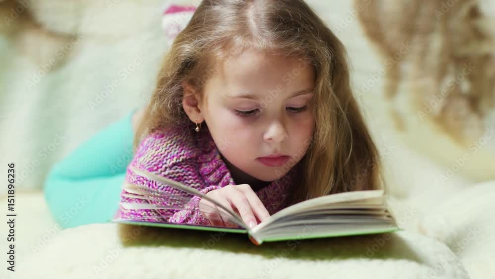 Portrait of little girl lying with book on the couch. Portrait of little girl lying with book on the couch.