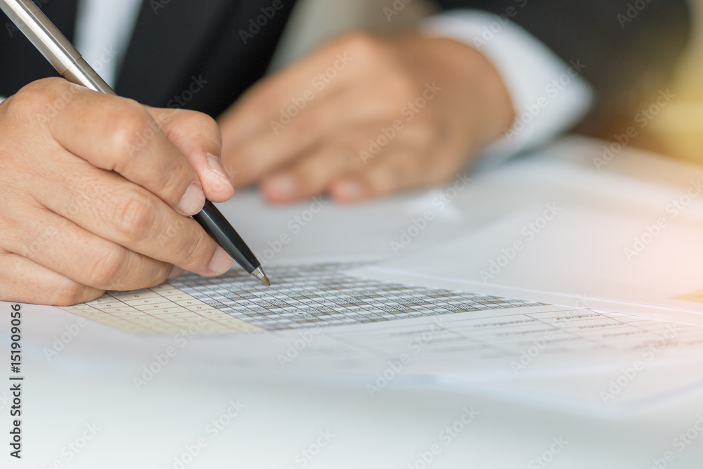 Hand holding pen for analyzing financial data and counting on document chart, business concept. Hand holding pen for analyzing financial data and counting on document chart, business concept.