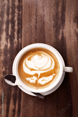 Cup of coffee with latte art on wooden background