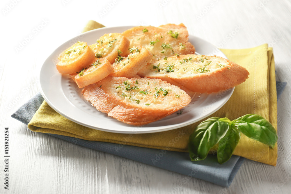Plate with tasty garlic French bread slices and green napkin Plate with tasty garlic French bread slices and green napkin