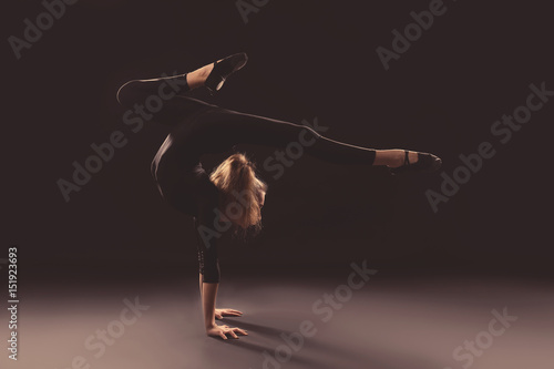 Young girl doing gymnastics on dark background
