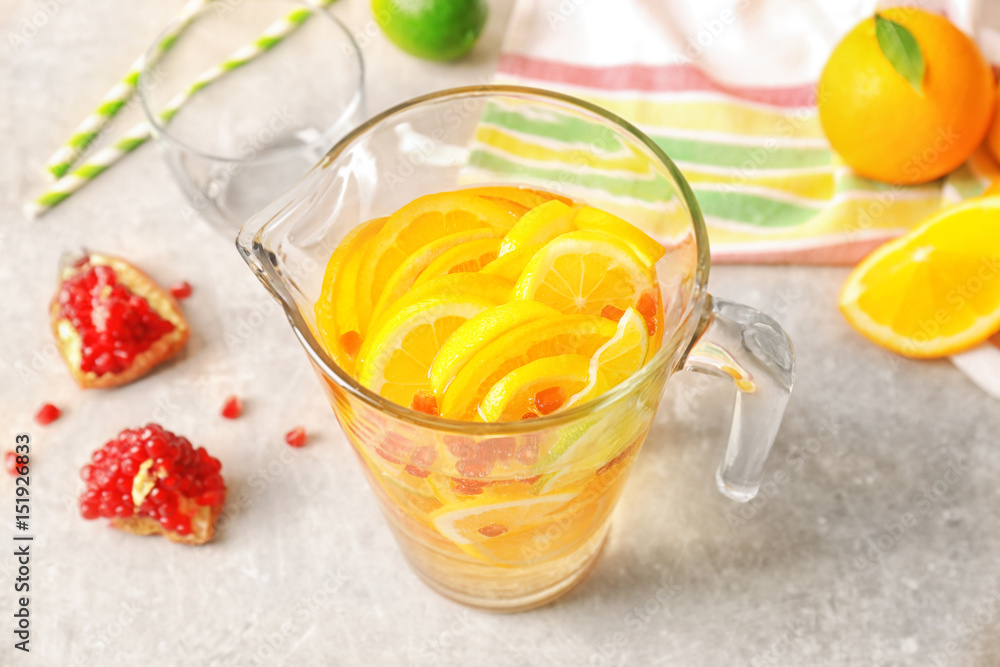 Glass jug with refreshing citrus fruits cocktail on light background Glass jug with refreshing citrus fruits cocktail on light background