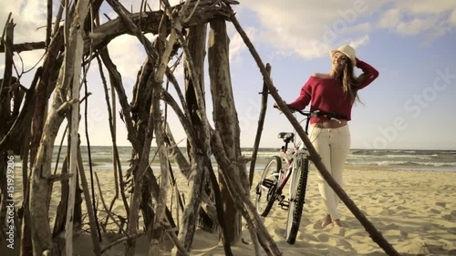 Young long hair woman enjoying windy summer day on sandy beach dunes  Active girl with bicycle on seaside. Female tourist resting near to sea  on fresh air 4K ProR es HQ codec photo