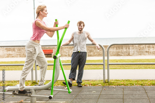 Man and woman exercising on elliptical trainer. © anetlanda