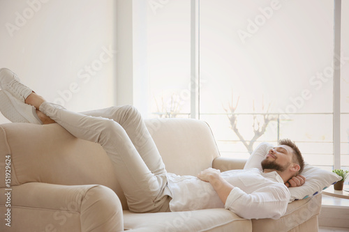 Happy young man resting on sofa