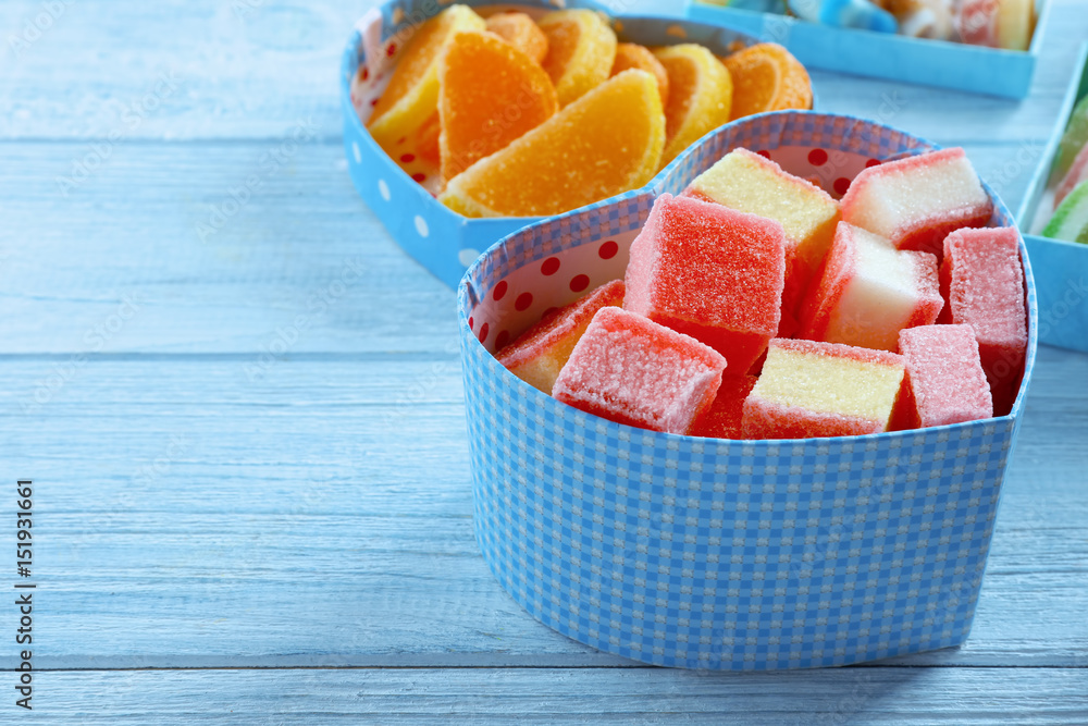 Heart-shaped box with tasty jelly candies on wooden background Heart-shaped box with tasty jelly candies on wooden background