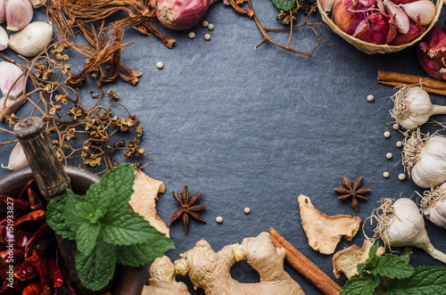 Various dried herbs with papermint on black stone background