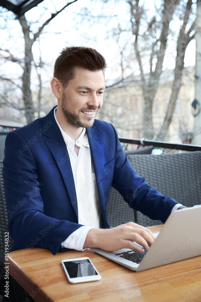 Young businessman working with laptop in outdoor cafe Young businessman working with laptop in outdoor cafe