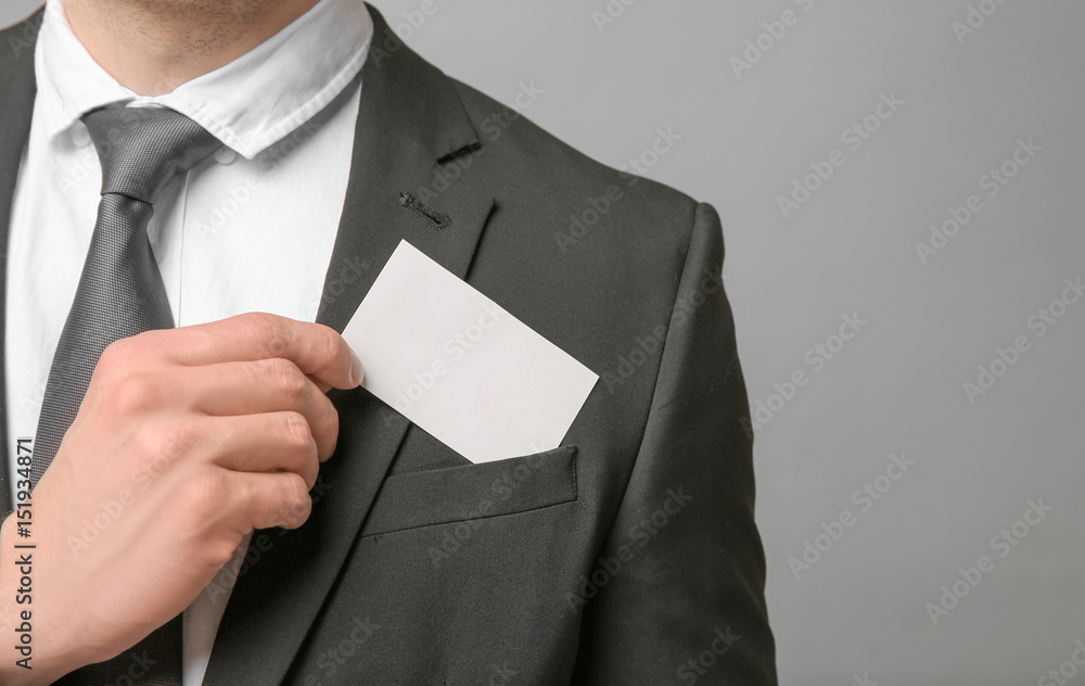 Handsome young man with business card on grey background, closeup Handsome young man with business card on grey background, closeup