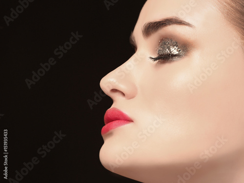 Beautiful young woman with holiday make up on black background