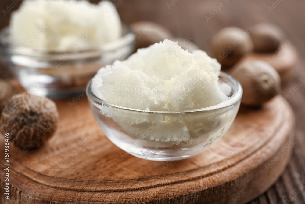 Shea butter in bowls on wooden background, close up