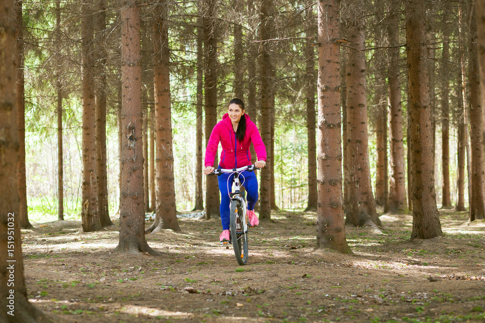 Walking through the forest on a bicycle in the summer forest of an athletic young woman Walking through the forest on a bicycle in the summer forest of an athletic young woman