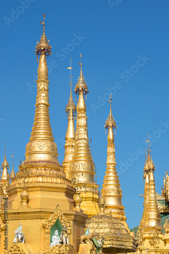 The tops of the golden stupas of the Shwedagon pagoda against the blue sky. Yangon, Myanmar