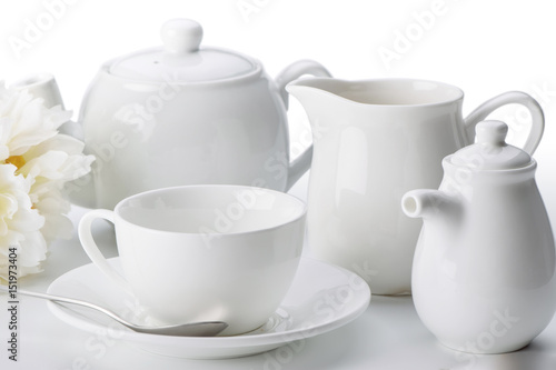 China tea set: cup with saucer and spoon, teapot, milk jug close-up isolated on white background
