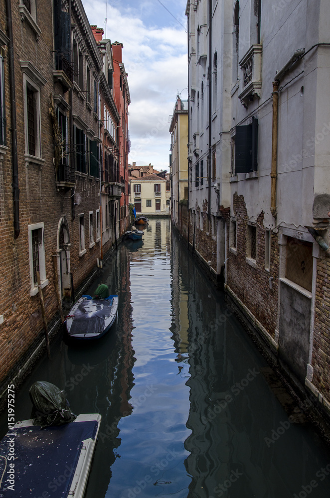 blue sky reflection in canal, view of canal in venice with boat and a blue sky strip reflected. Venice, italy, vertical