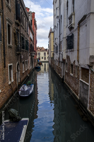 blue sky reflection in canal, view of canal in venice with boat and a blue sky strip reflected. Venice, italy, vertical © marinzolich