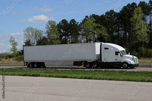 A Large Semi-Truck Travels Along a US Highway. All markings have been removed.