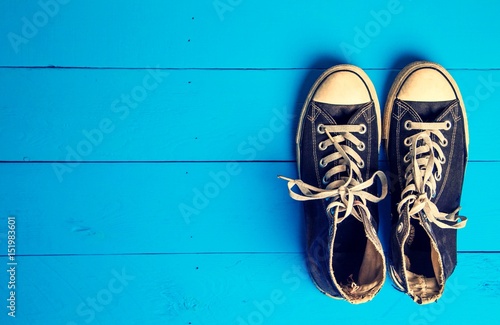 Dirty gumshoes on blue wooden background