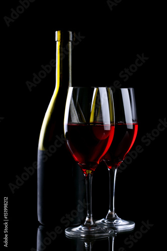 Wine glass and bottle with red wine isolated on black