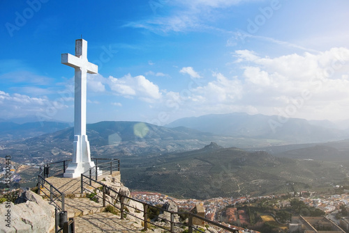A white cross over Jaen town at the mountain, a symbol of the town with Sierra Magina mountains on background on sunny day, Andalusia region, Spain.