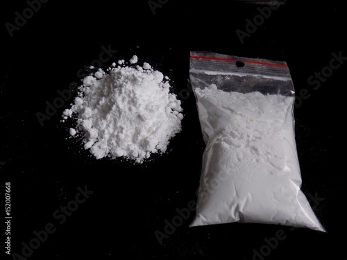 Cocaine drug powder bag and pile on black background