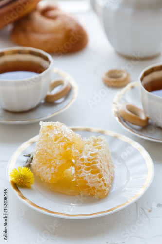 Honeycomb on a plate with tea cups on background