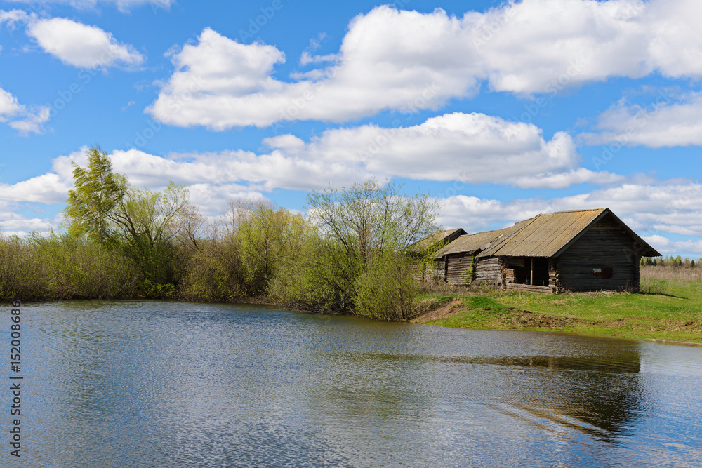 Fototapeta premium Old wooden house on the shore of the reservoir in the spring
