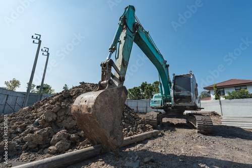 excavator on construction site, digger on gravel heap with shovel