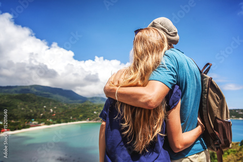 Young happy couple hugging and looking at a stunning beautiful tropical landscape from a height. Travel, adventure, honeymoon concept