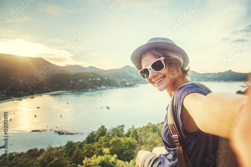 young woman traveler in sunglasses makes selfie with sea view photo