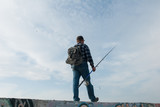 man with a fishing rod and a backpack goes fishing