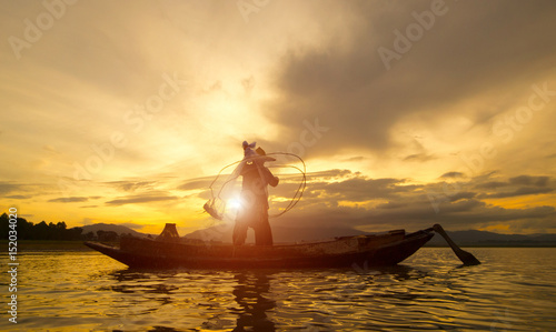 Silhouette of Myanmar fisherman on wooden boat ,Myanmar fisherman in action catching freshwater fish in nature river, Myanmar traditional fishermen at the sunset near Inle lake,Myanmar